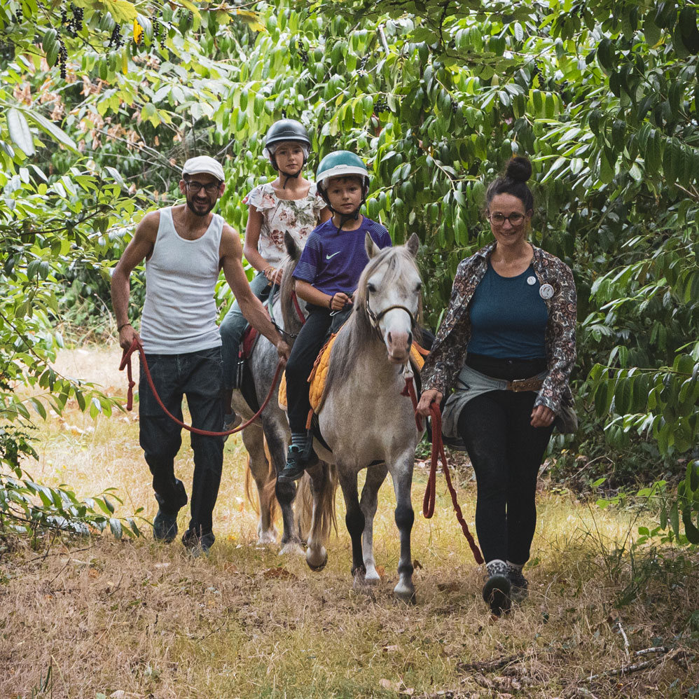 Enfants et parents en balade à poney en forêt